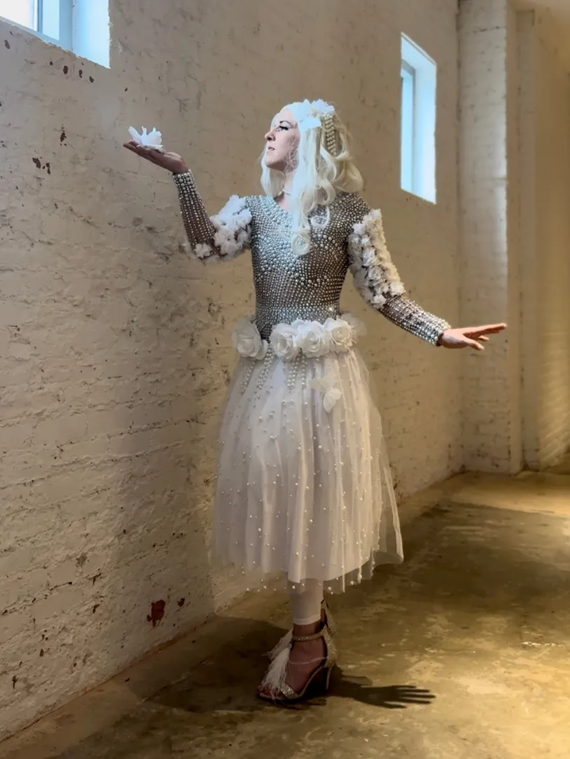 Dakota Fox in a silver and white costume in a brick studio