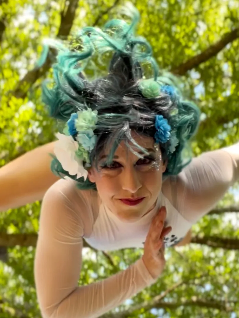 Dakota Fox in a teal flower headpiece in an aerial pose outdoors