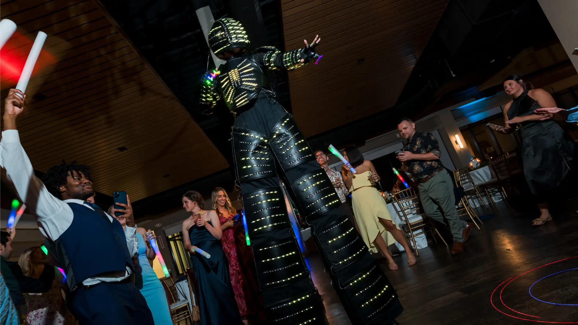 LED party robot stilt walker dancing with guests on a dark dance floor