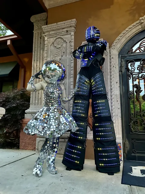 Two mirror ball stilt walkers in front of an ornate doorway