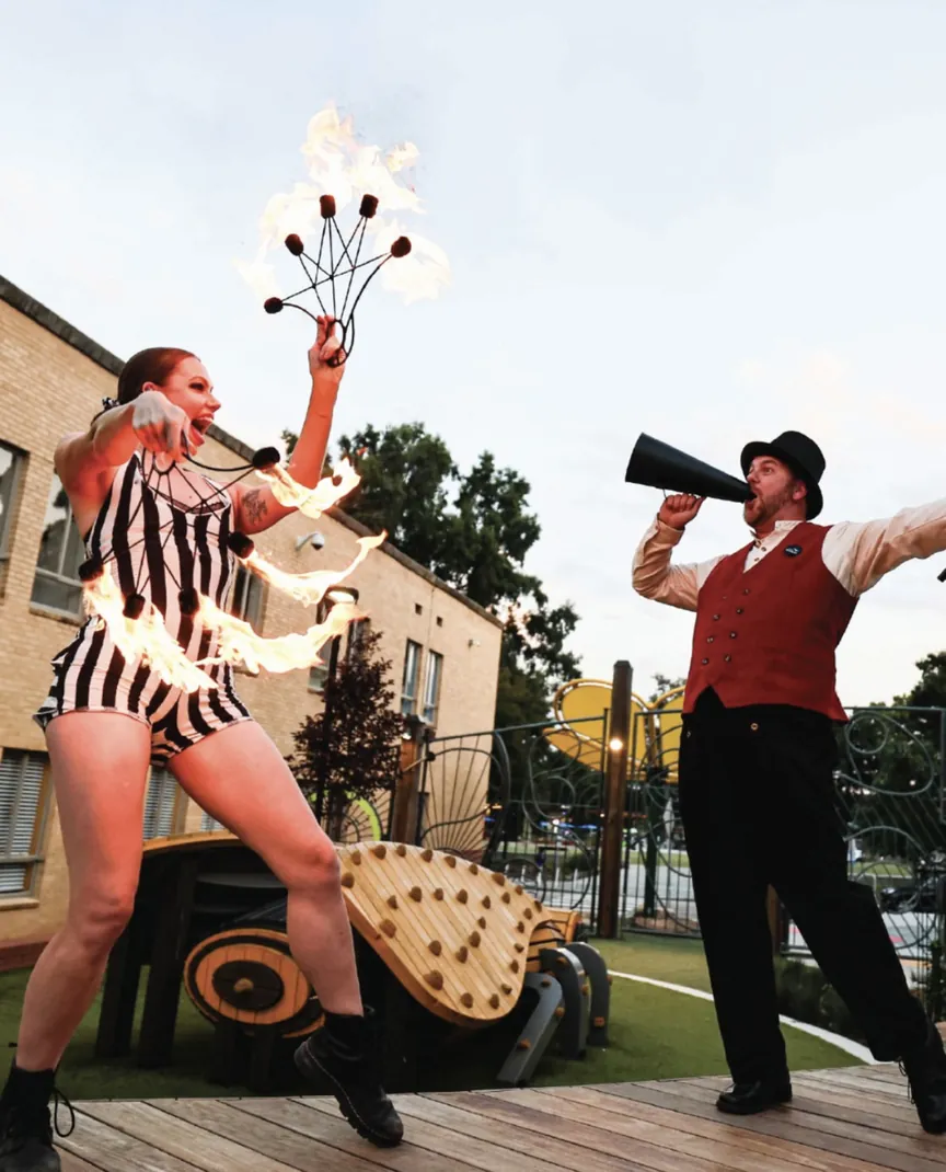 Stilt walker with a feather fan and a ringmaster with a megaphone